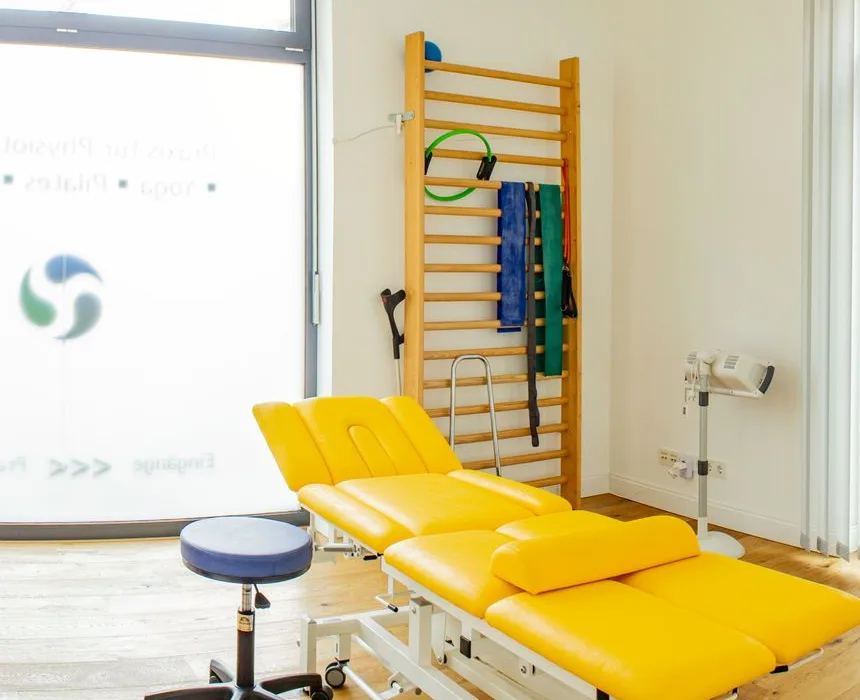 Behandlungsliege und Therapiegeräte im hellen Behandlungsraum