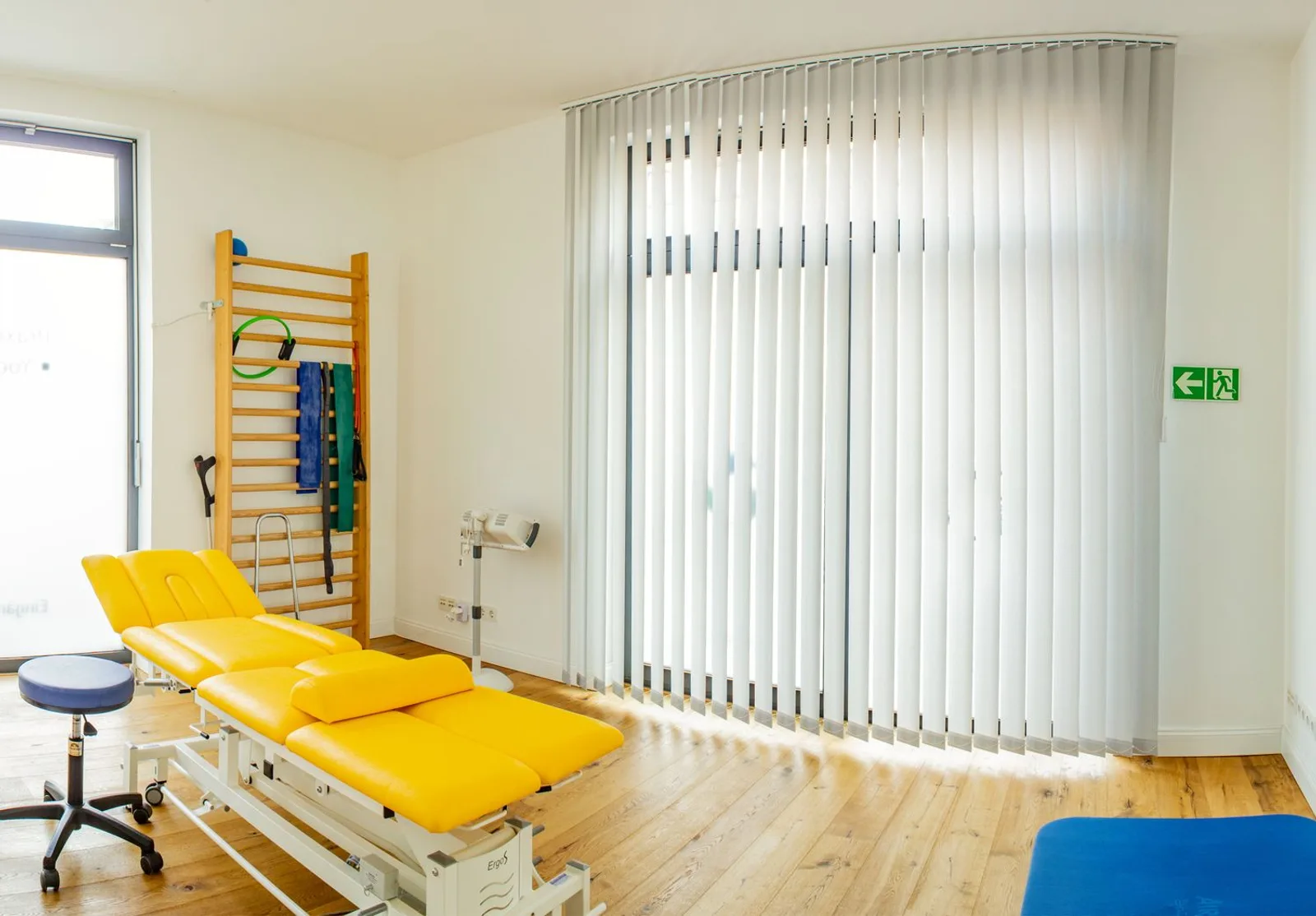 Heller, moderner Behandlungsraum der Praxis Richter mit Sprossenwand und Behandlungsliege